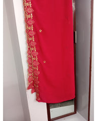 Red fabric with gold embroidery draped over a mirror on a white wall.