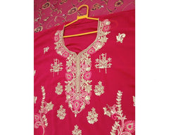 Pink embroidered garment on a hanger against a pink floral background