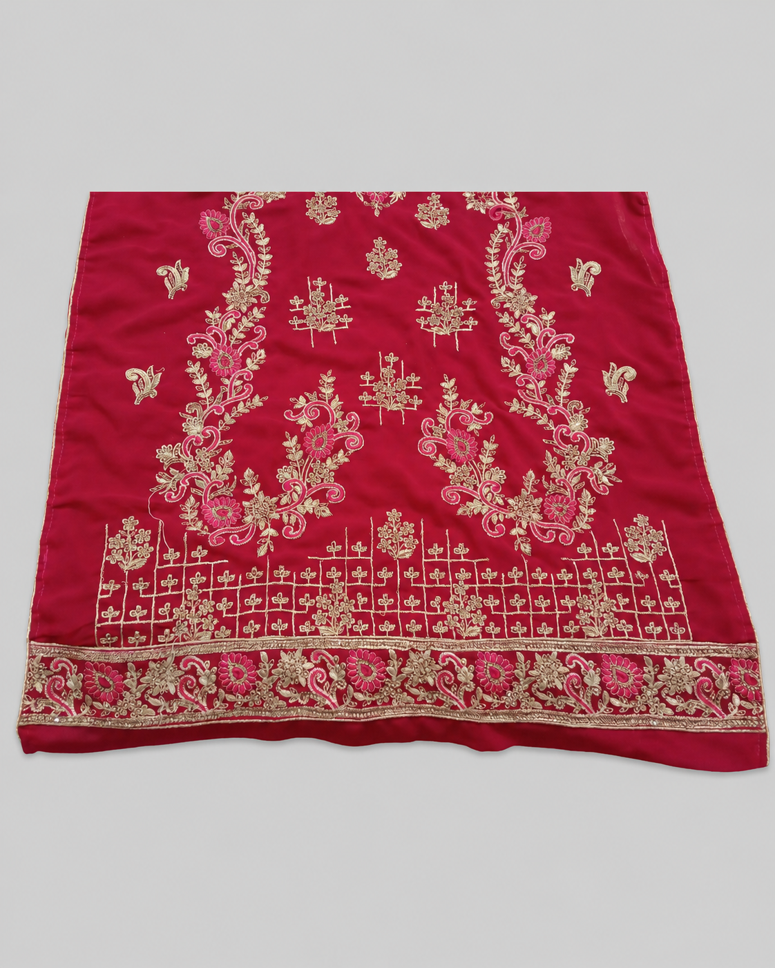Red fabric with gold and pink embroidery on a gray background
