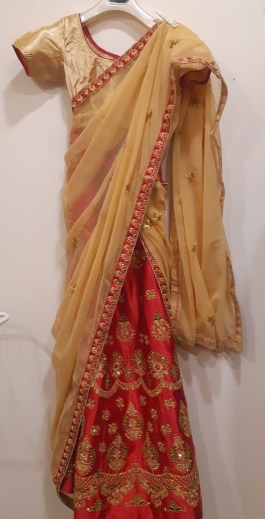 Half Saree with red and gold design on a plain background