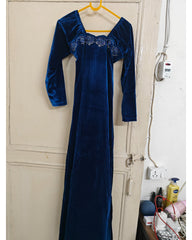 Blue velvet dress hanging on a door in a room with visible electrical outlets and a wall socket.
