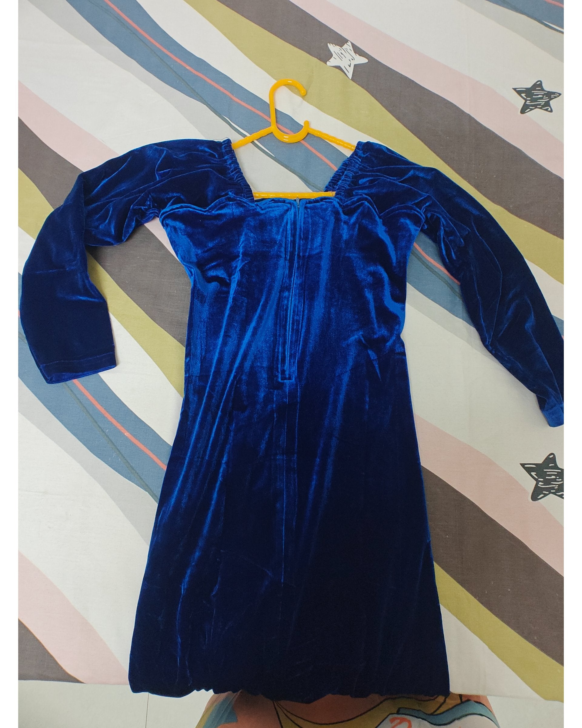 Blue velvet dress on a hanger against a striped background, back view