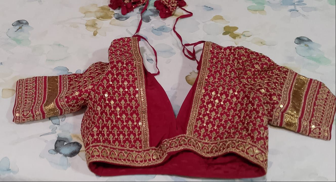 Back view of Red SABYASACHI embroidered blouse on a floral-patterned fabric background
