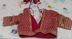 Back view of Red SABYASACHI embroidered blouse on a floral-patterned fabric background