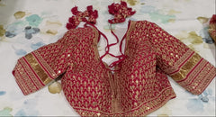 front view of Red Sabyasachi embroidered blouse with gold details on a floral-patterned surface
