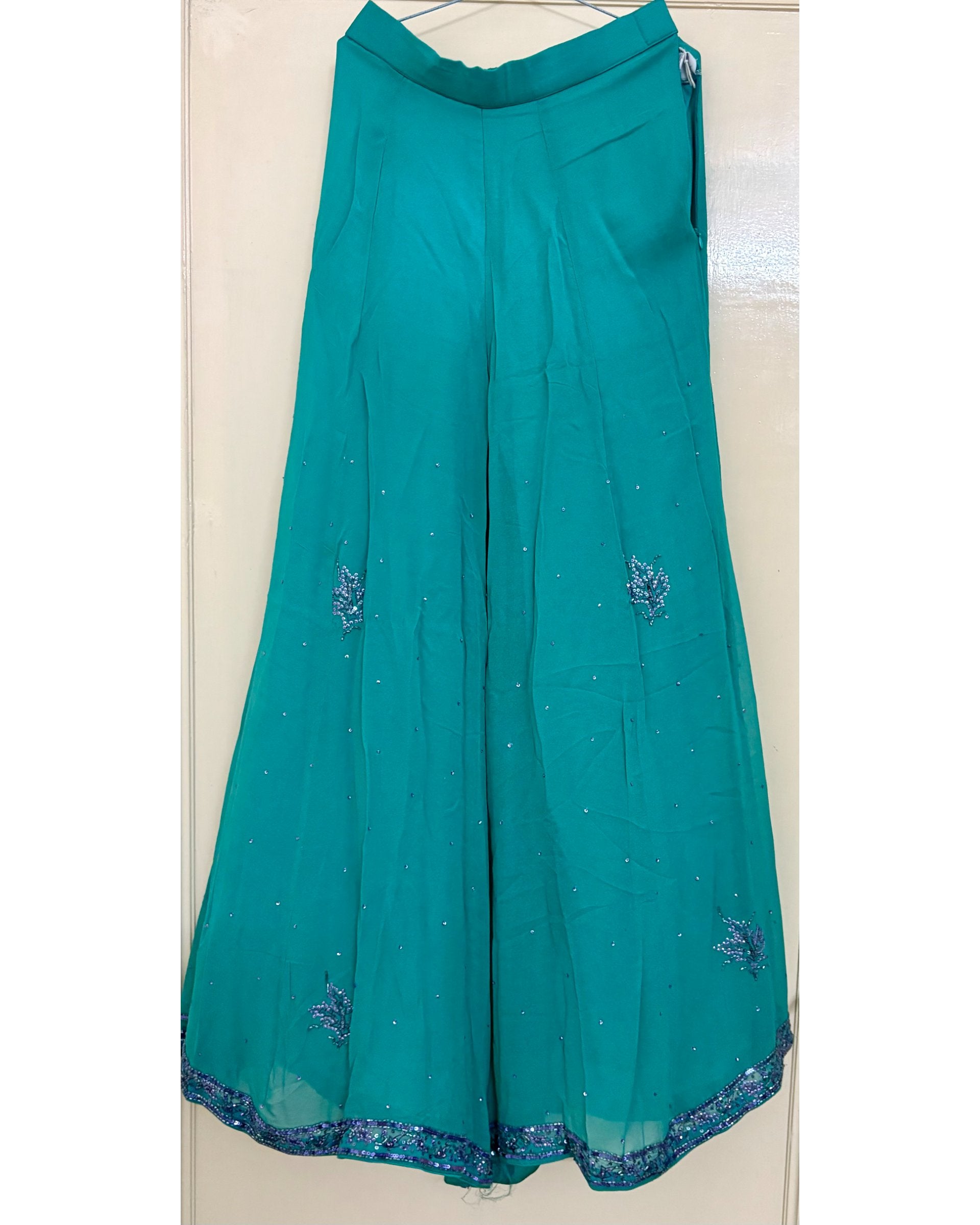 Teal pants with sequin embroidery on a white background