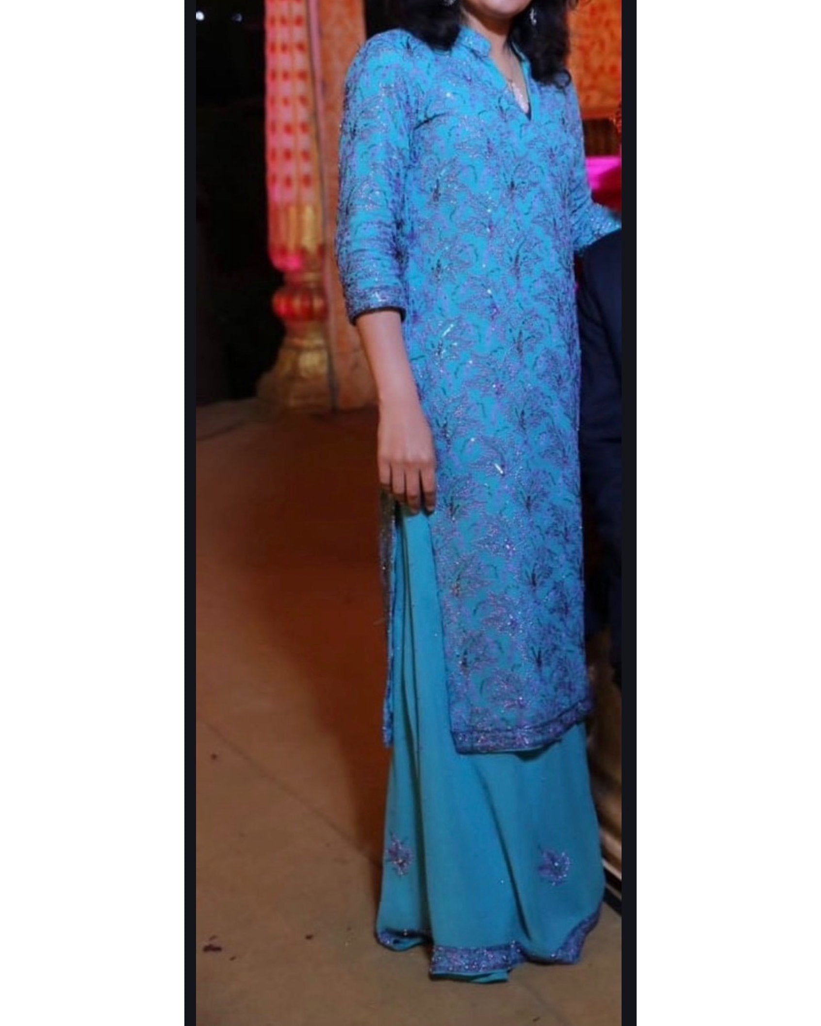 Person wearing a blue embroidered Indian traditional outfit with a blurred background