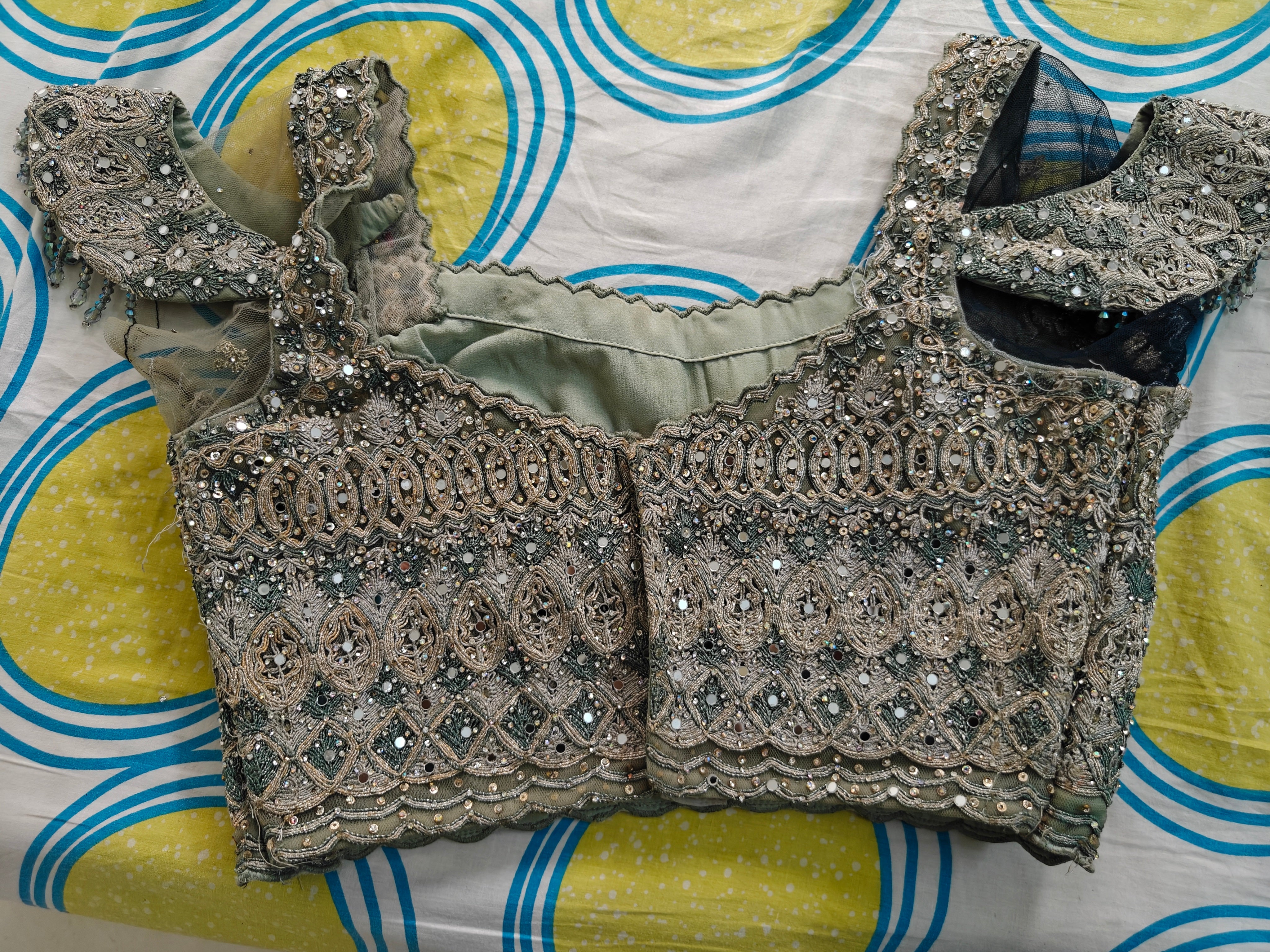 Decorative silver blouse with intricate patterns on a colorful fabric background