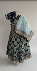 Traditional embroidered outfit with a blue dupatta on a hanger against a neutral background