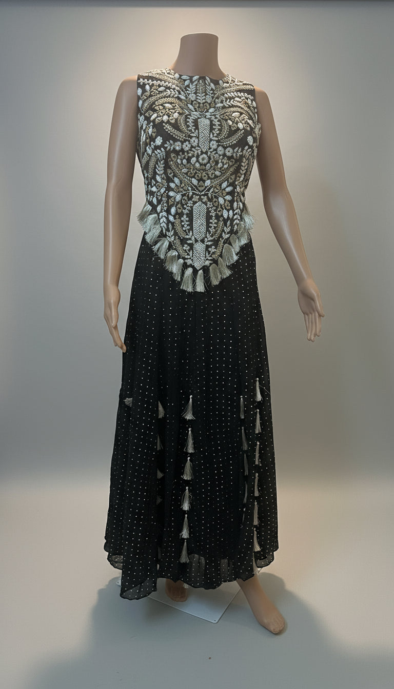 Mannequin wearing a black dress with intricate silver embellishments on a plain background