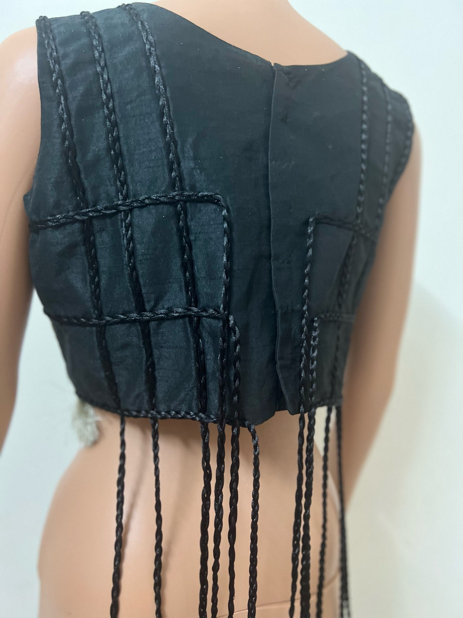 back view of Black sleeveless top with fringe details on a plain background