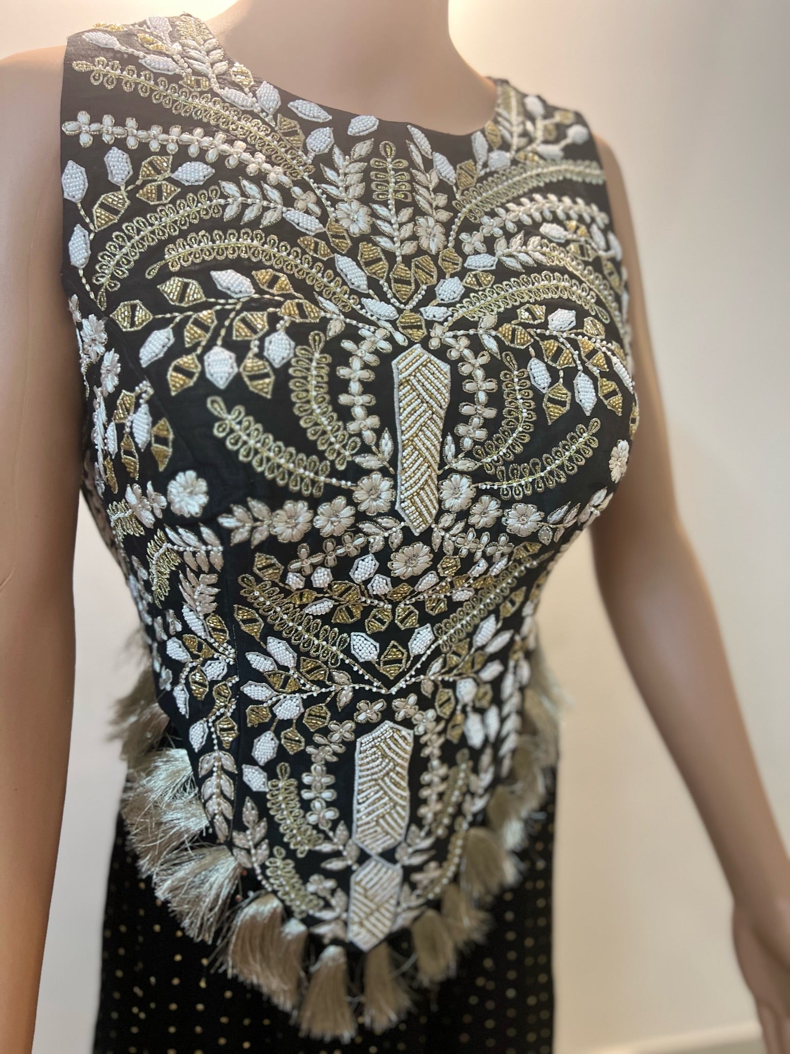 Mannequin wearing a black dress with gold and white embroidery