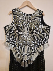 Black sleeveless choli top with intricate white and gold embroidery on a beige background